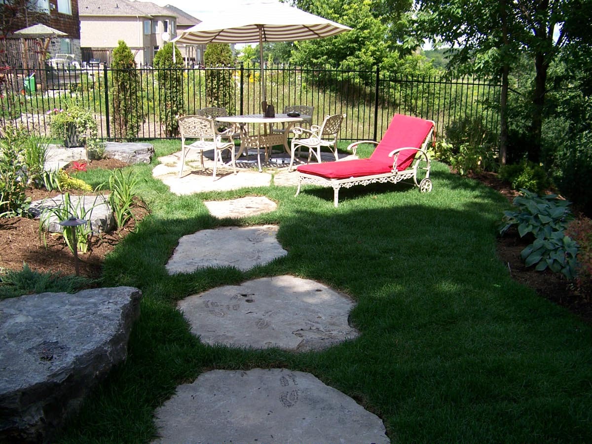Garden with stone path and patio furniture.