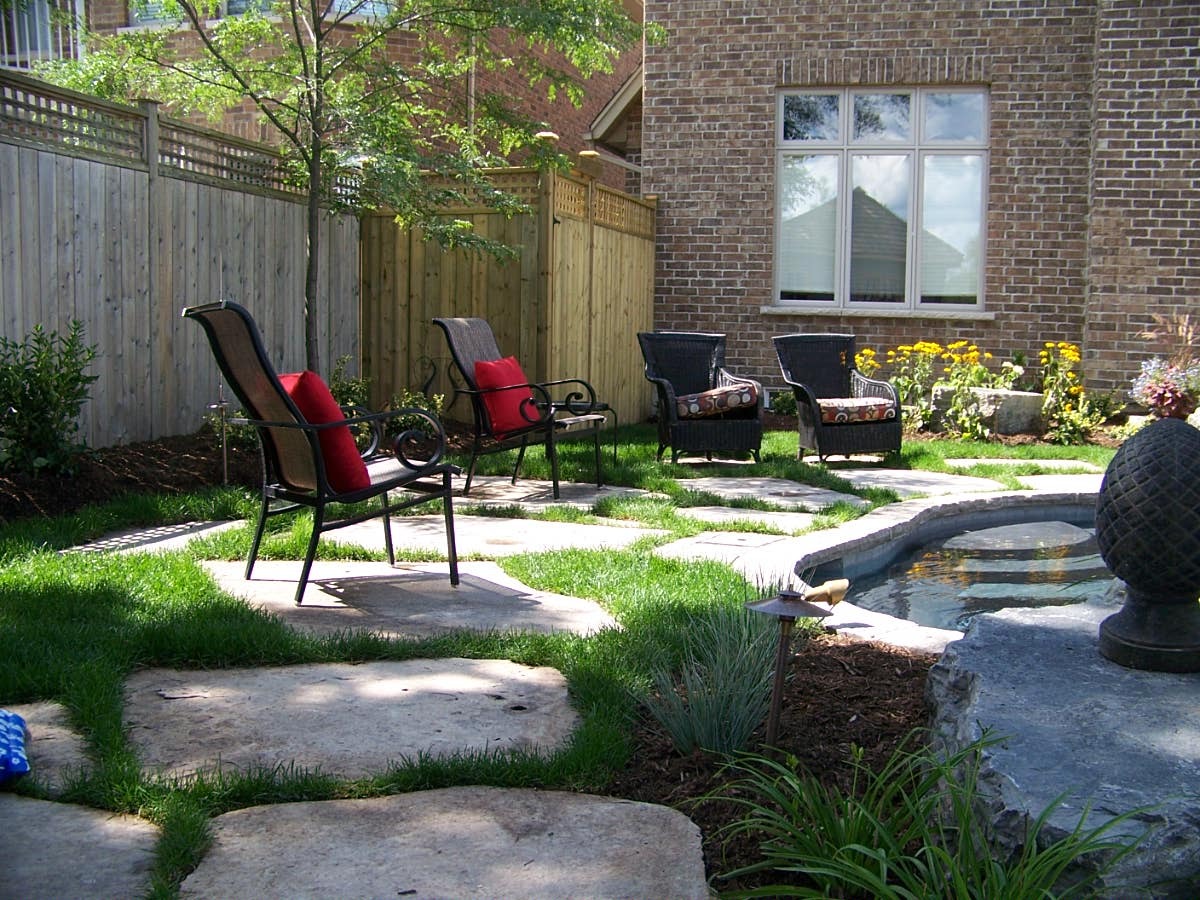 Backyard with chairs, pond, and brick wall.