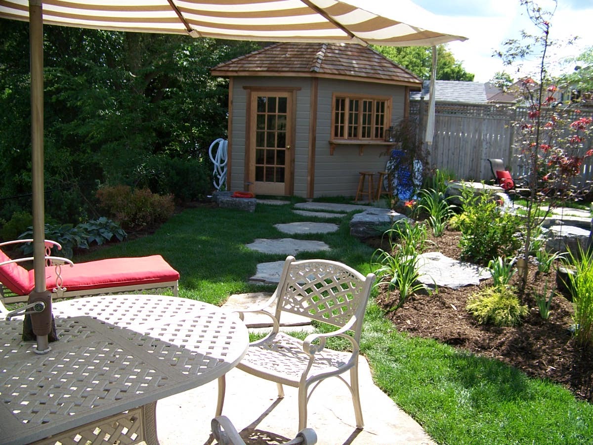 Backyard with patio, umbrella, and small garden house.