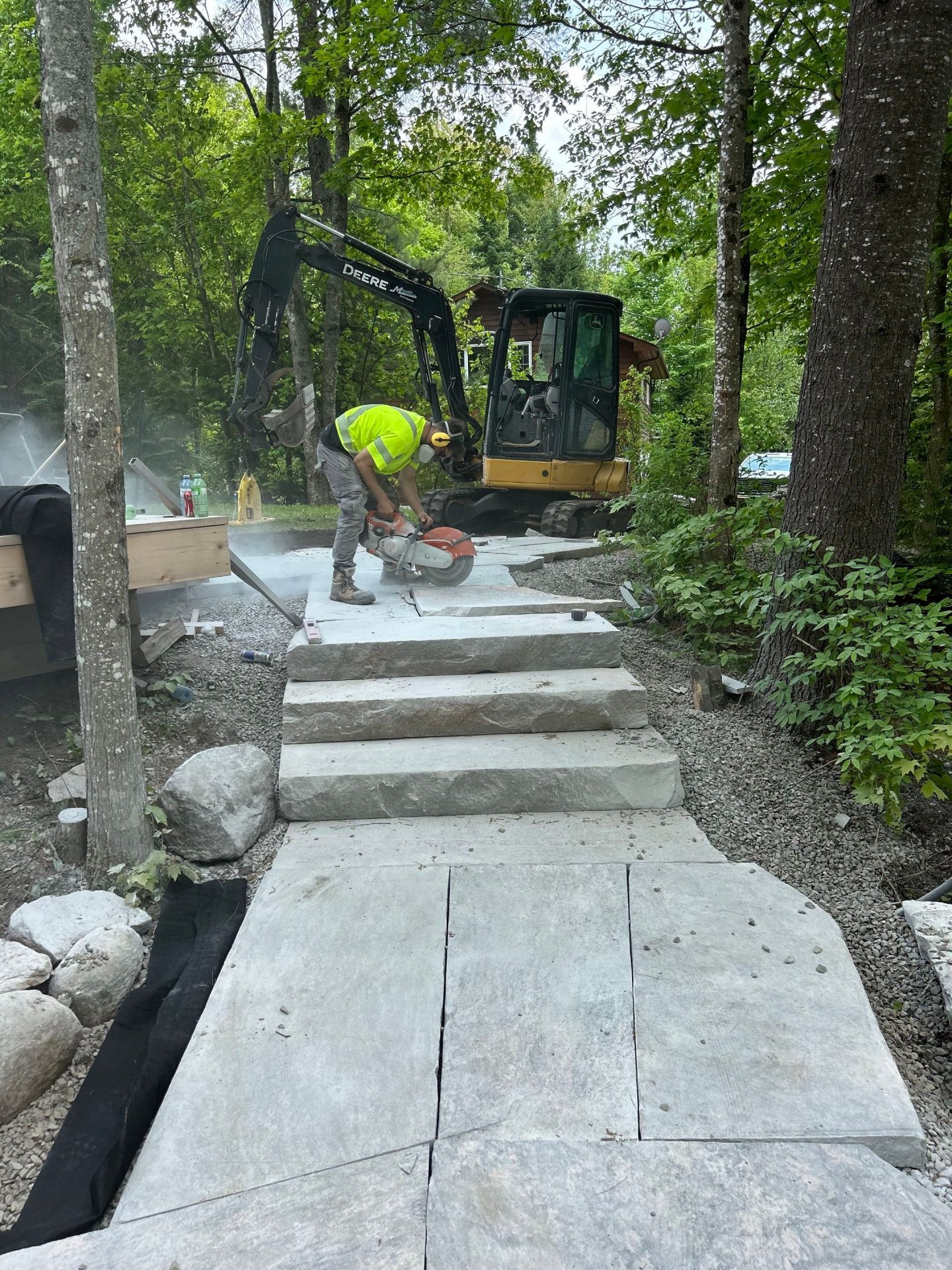 Worker cutting stone on outdoor construction site.