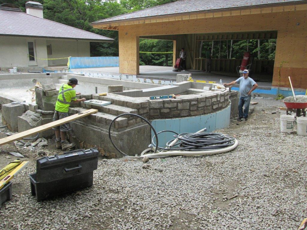 Construction workers building a pool structure outdoors.