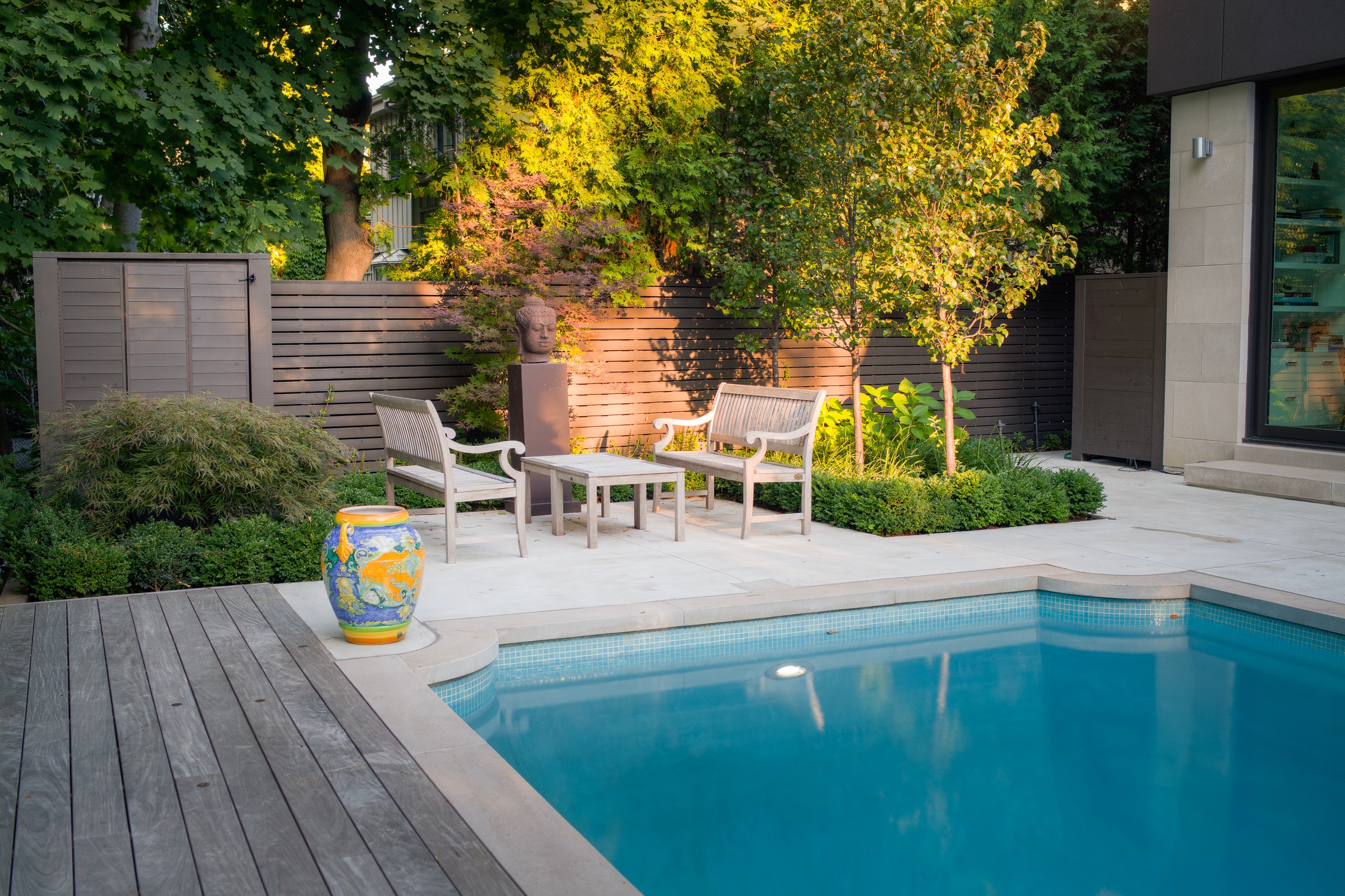 Luxury backyard pool with garden seating area.