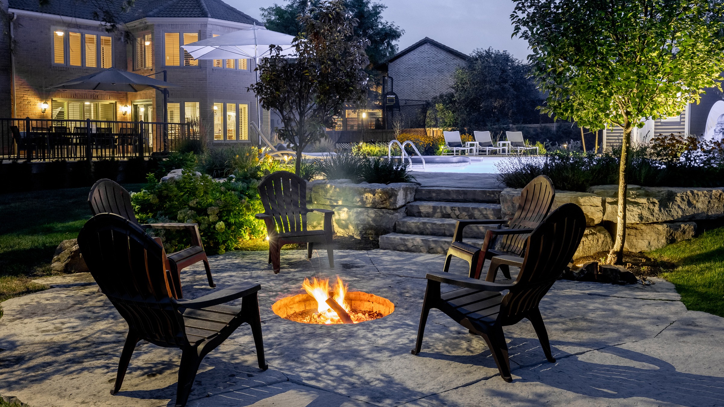 Backyard fire pit with chairs and pool.