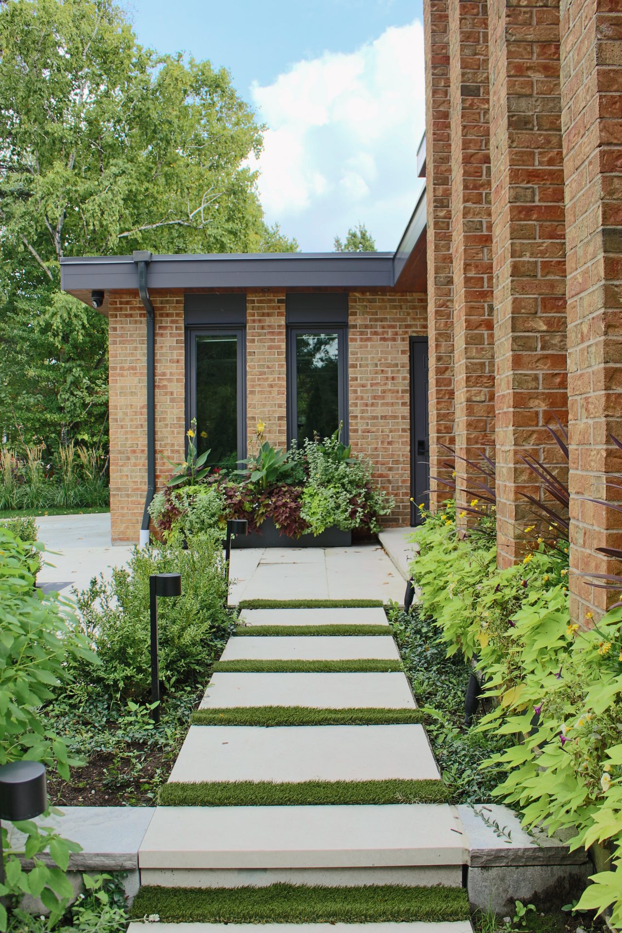 Modern house entrance with lush garden pathway