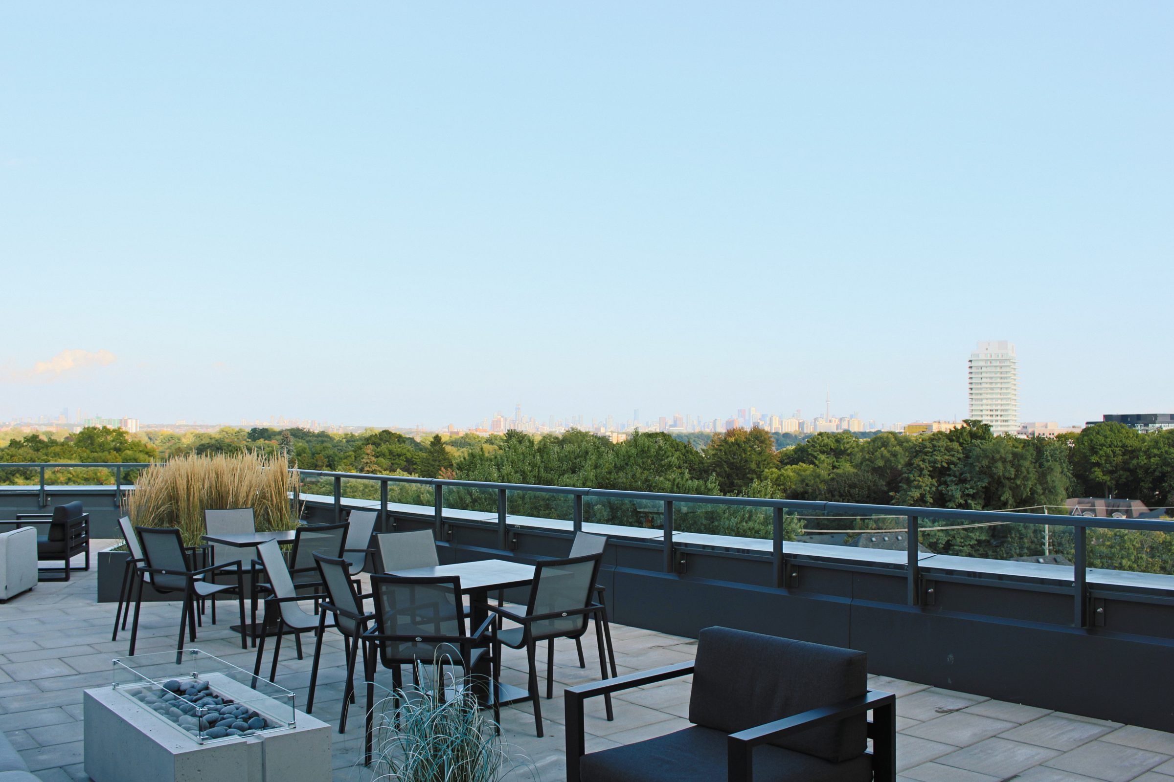 Rooftop patio with chairs, trees, and skyline view.