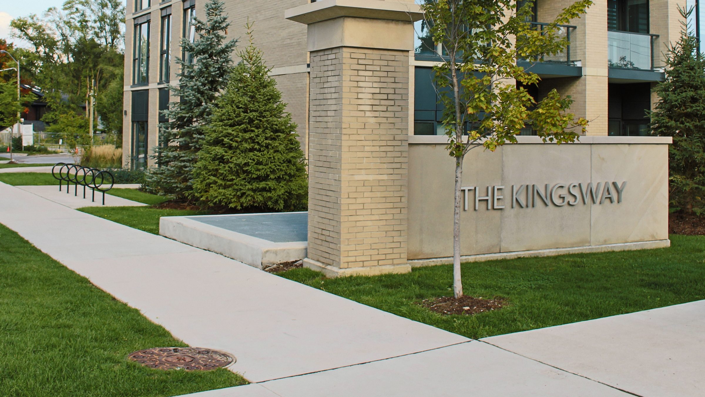 The Kingsway apartment entrance with trees and sidewalk.