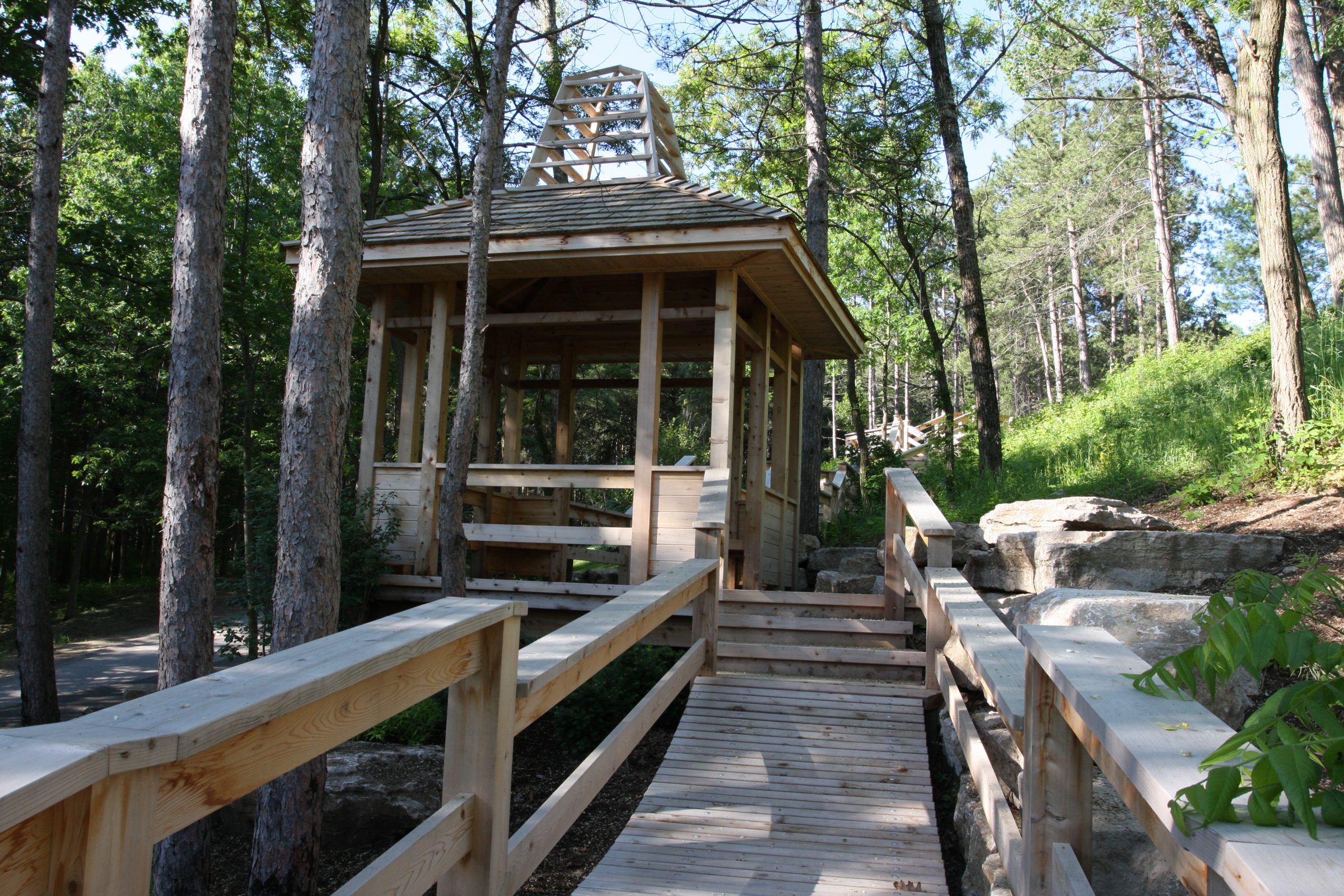 Wooden gazebo surrounded by trees and pathway