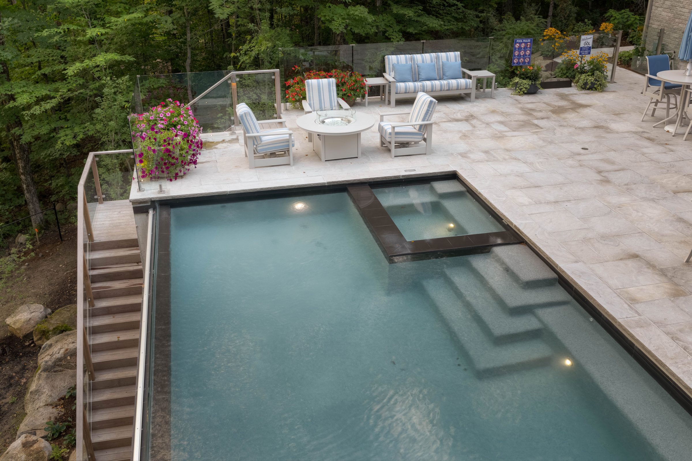 Outdoor pool with patio seating and plants.