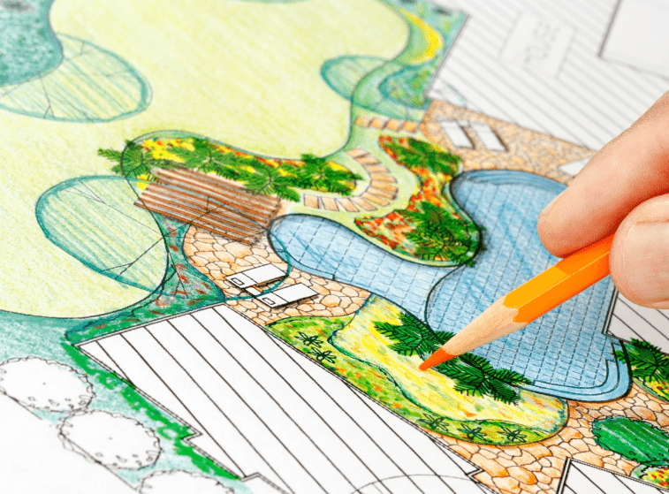 Person drawing detailed landscape design blueprint.