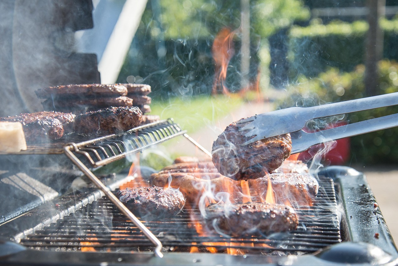 Grilling burgers on a barbecue with flames.