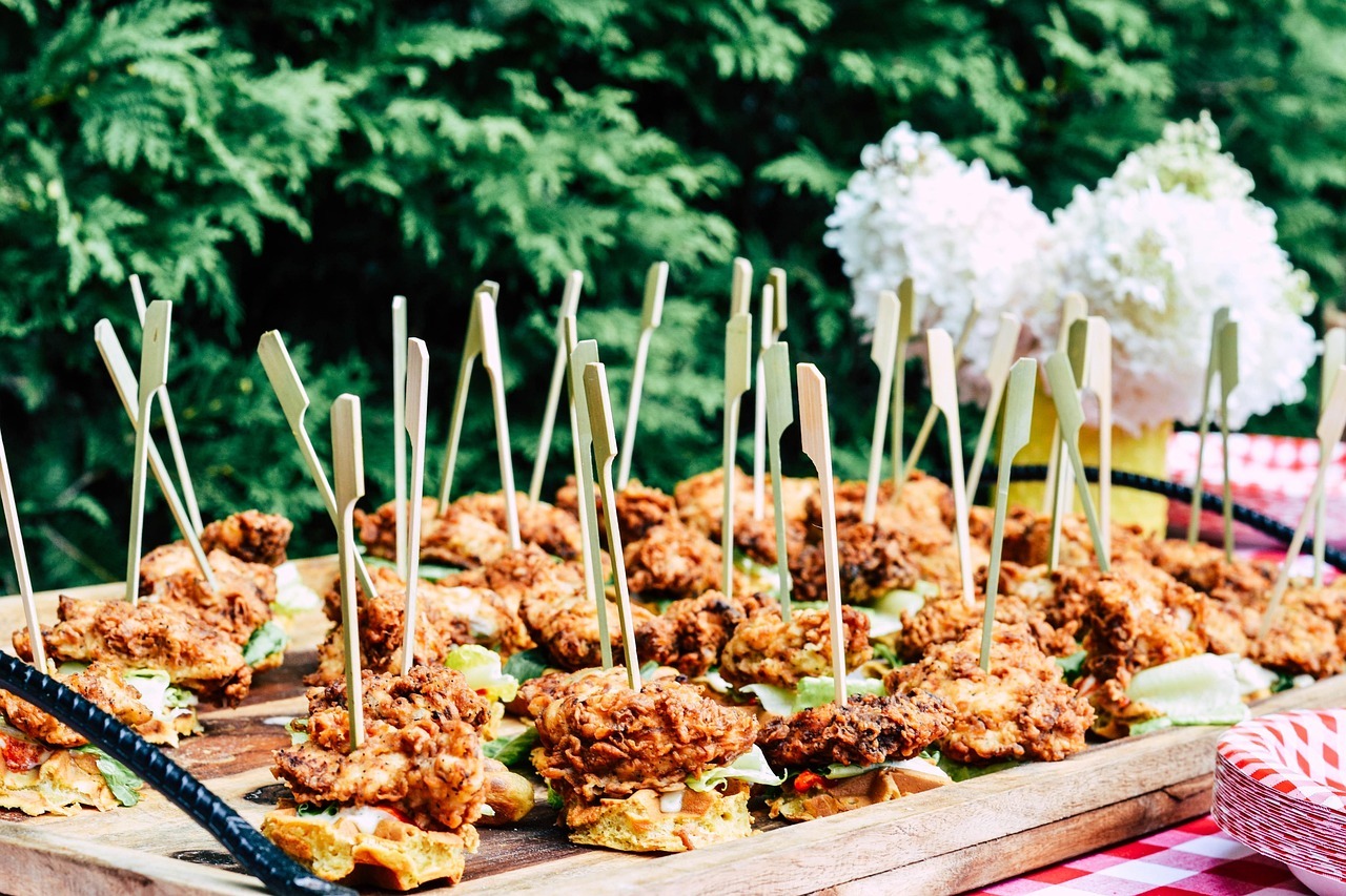 Fried chicken skewers on wooden platter outdoors