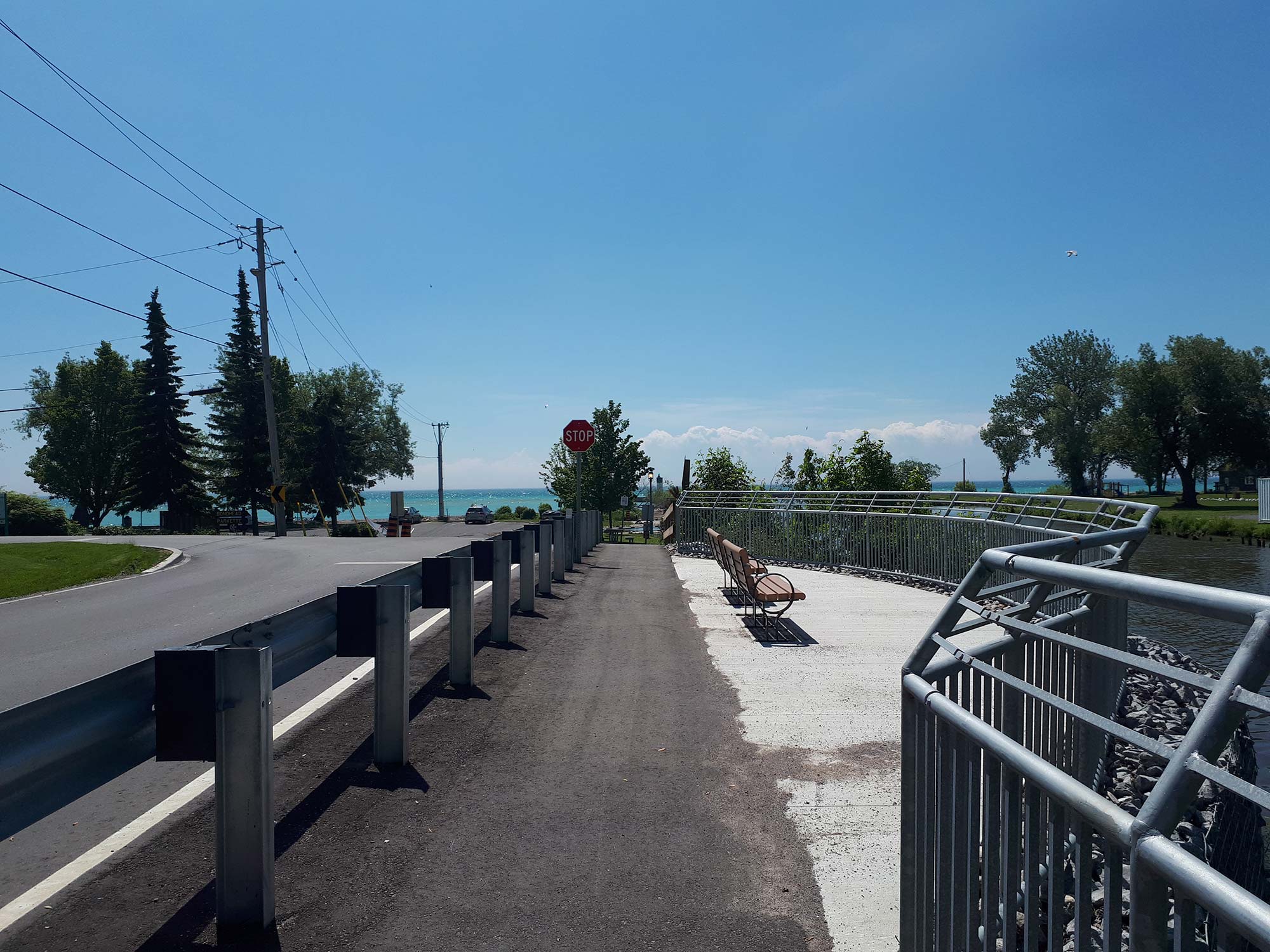 Lakeside path with benches and clear blue sky.
