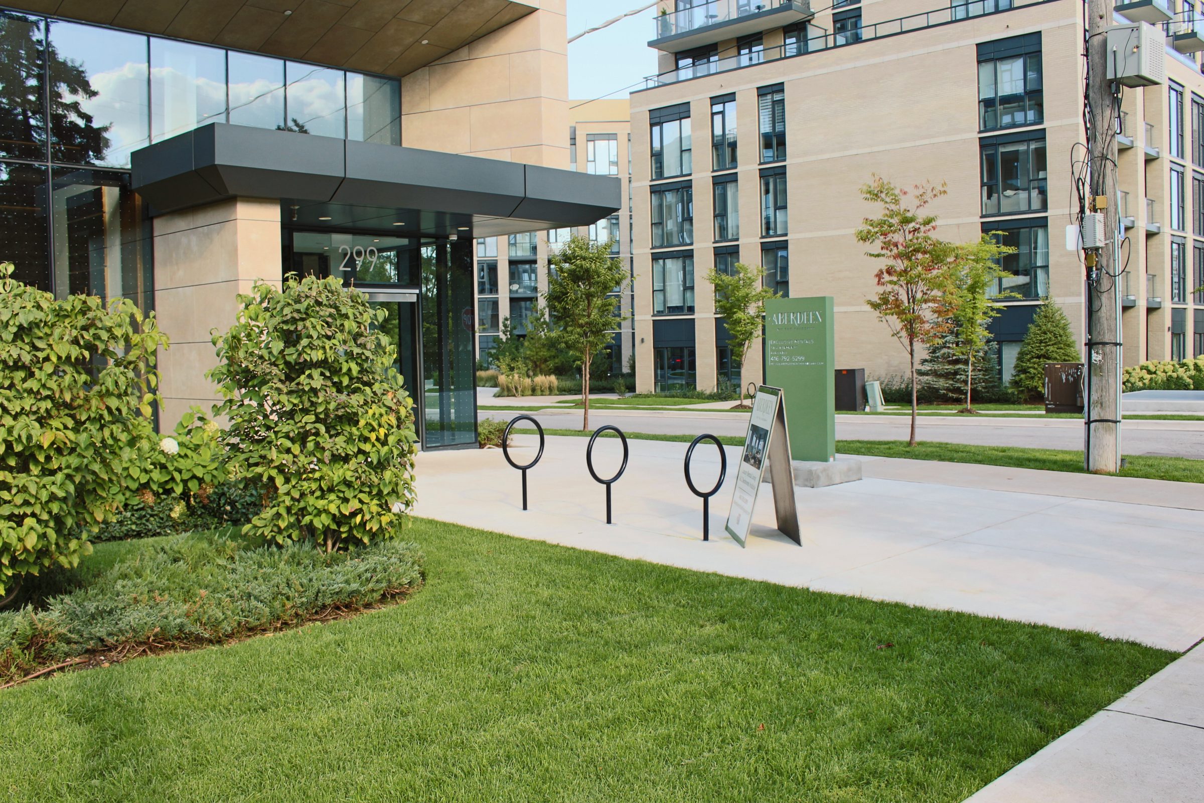 Modern building entrance with bike racks and greenery.