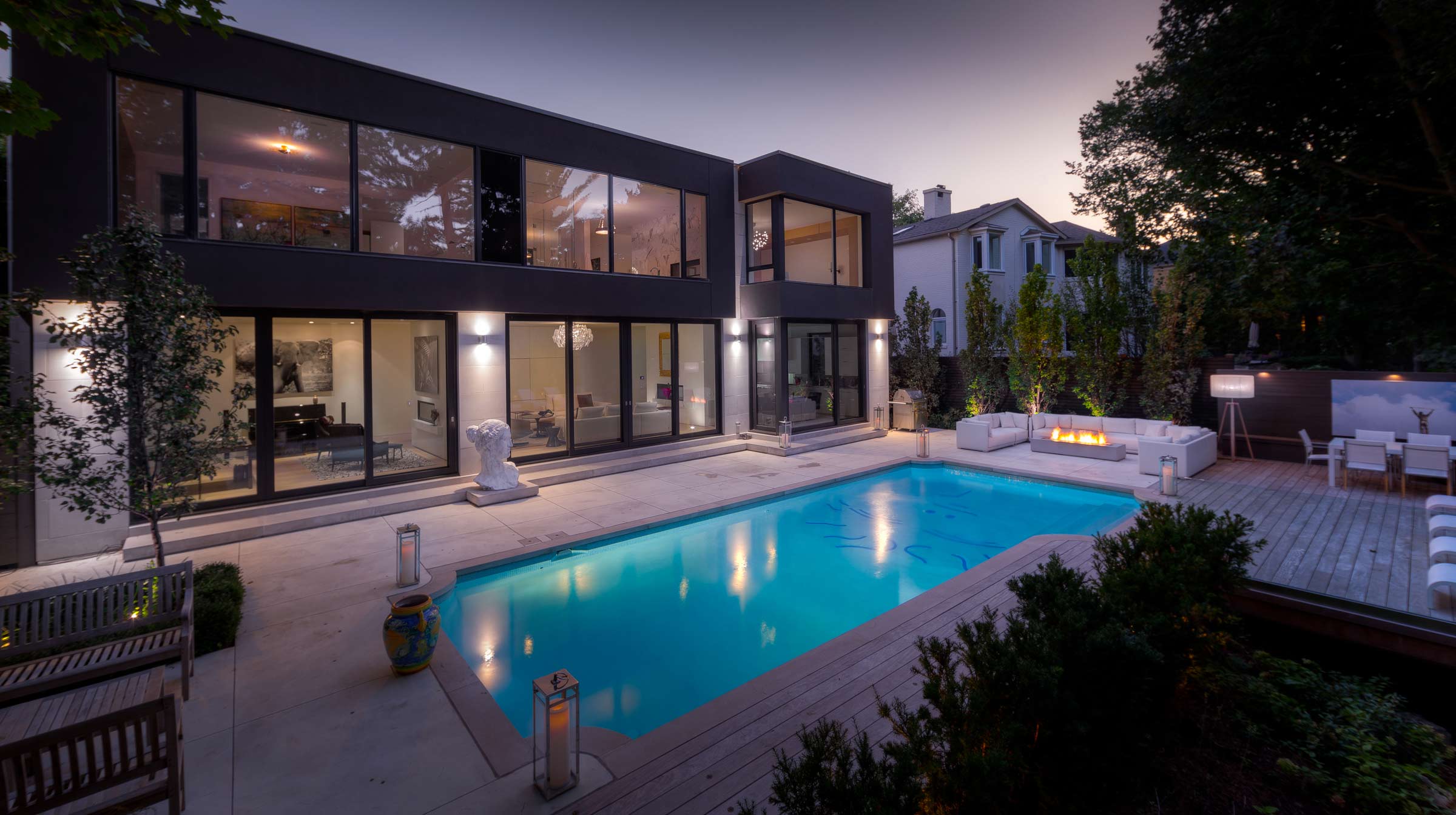 Modern luxury home with backyard pool at dusk.