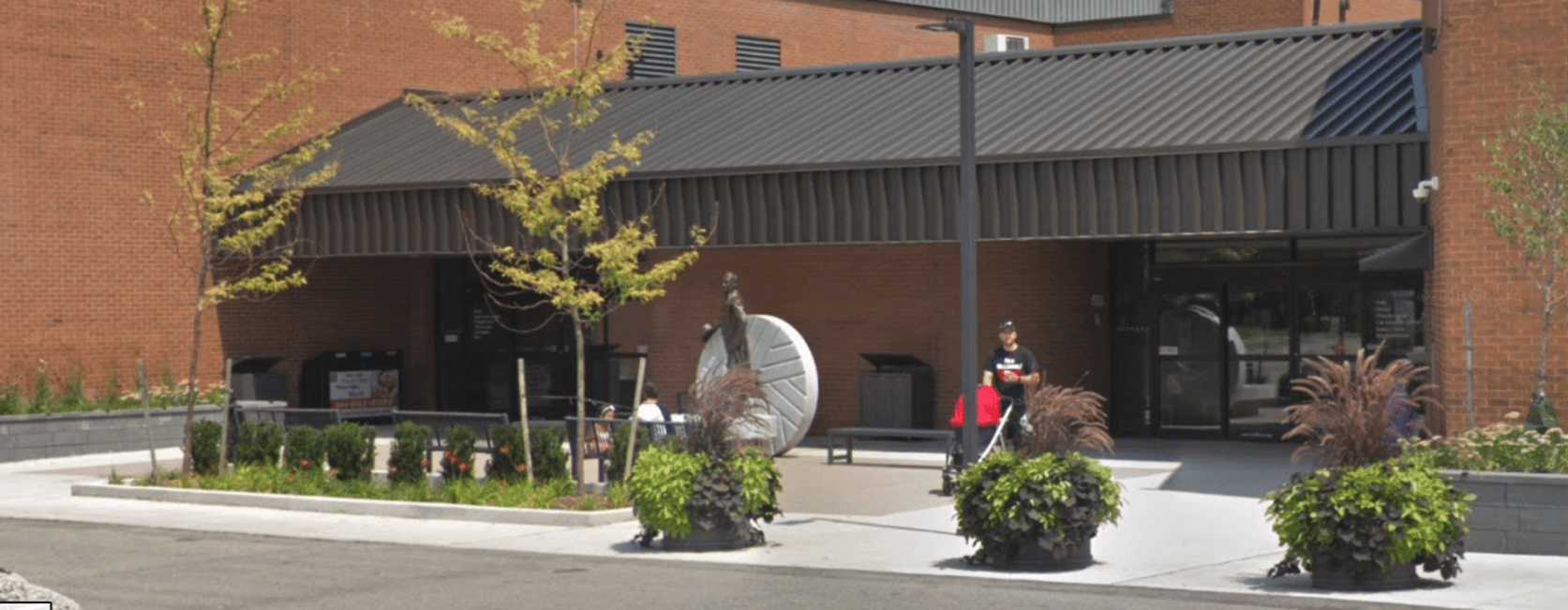 Building entrance with statue, plants, and people outside.