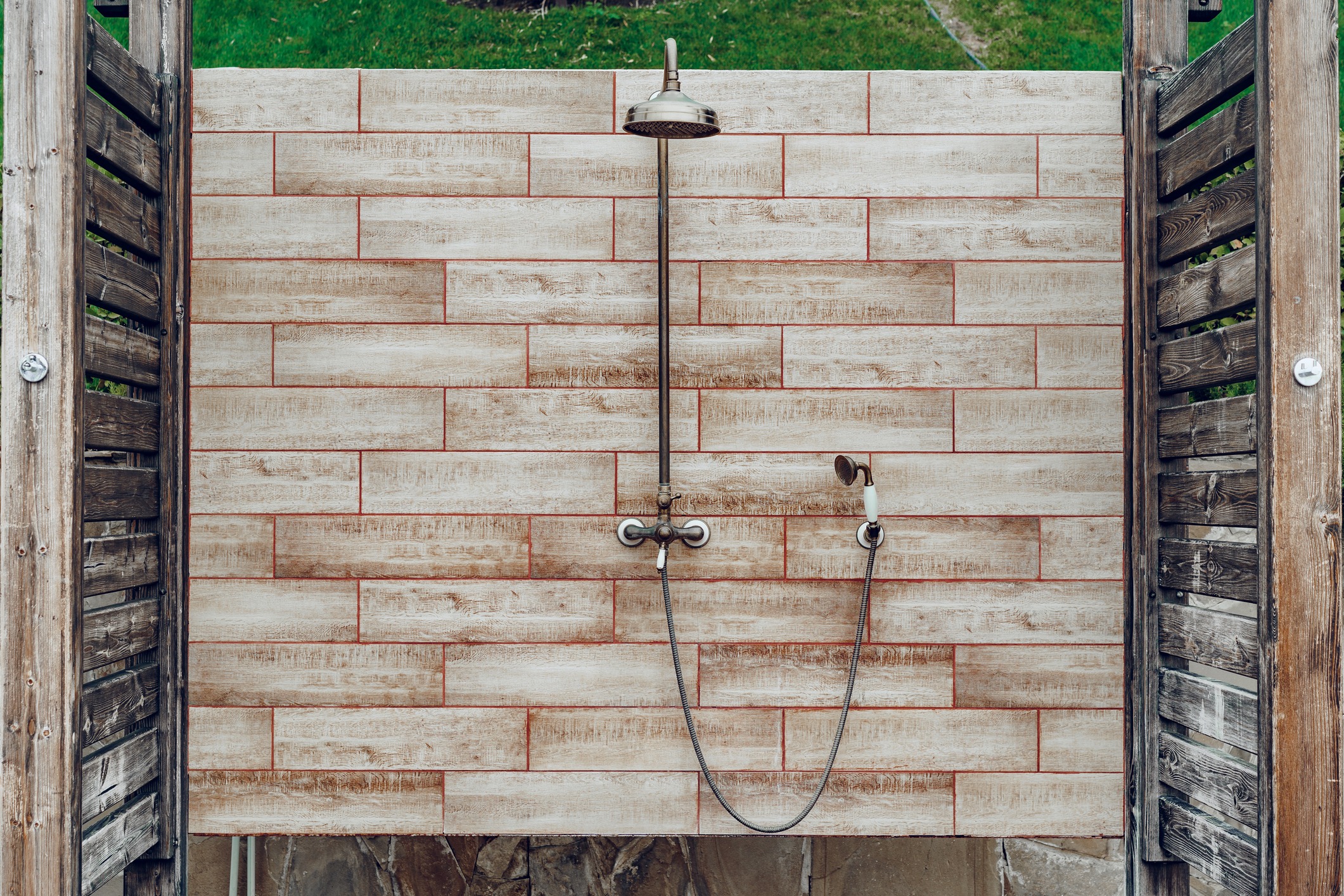 Outdoor shower with wooden panels and stone tiles.