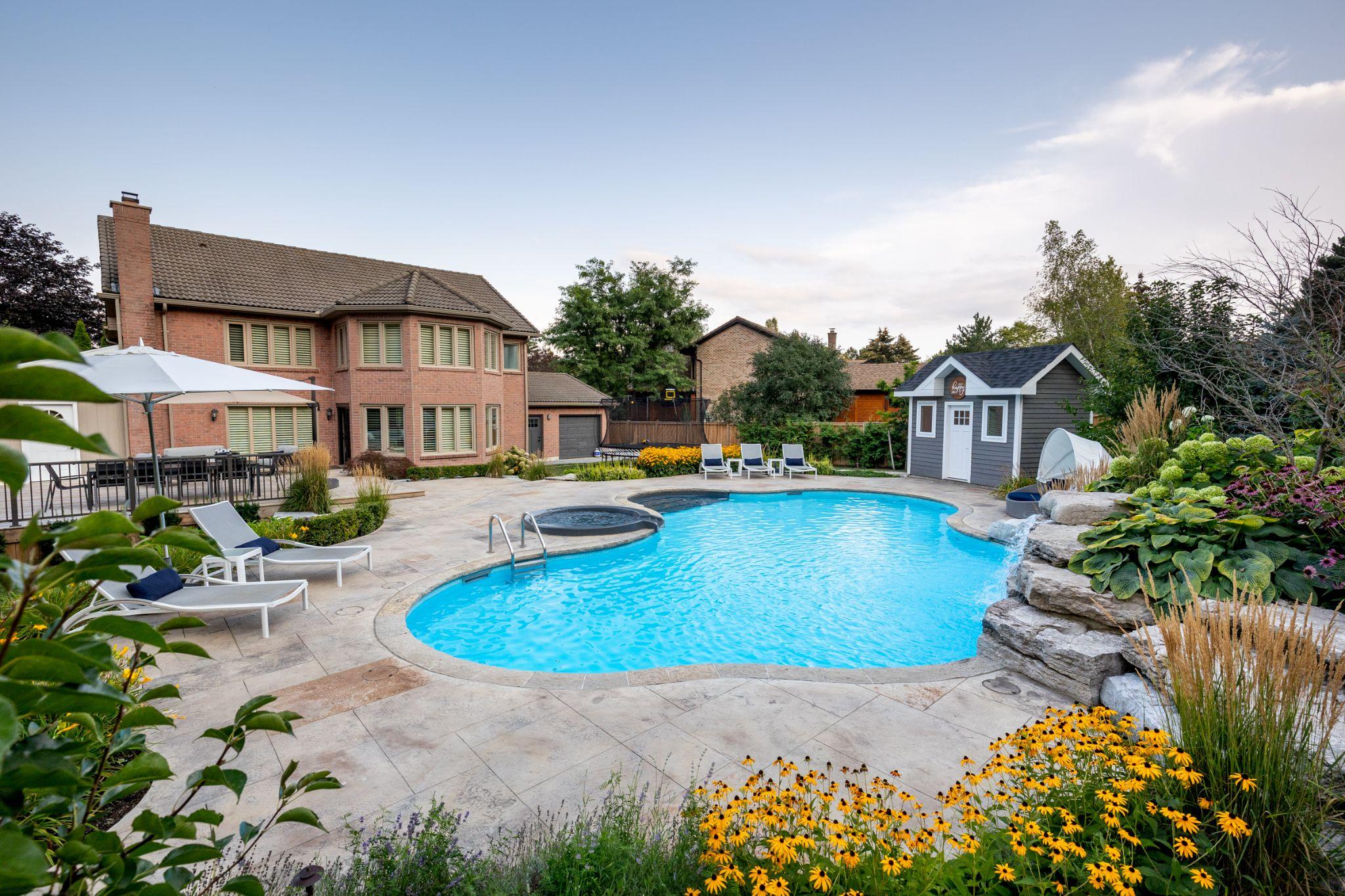 Backyard pool with waterfall feature and garden beds
