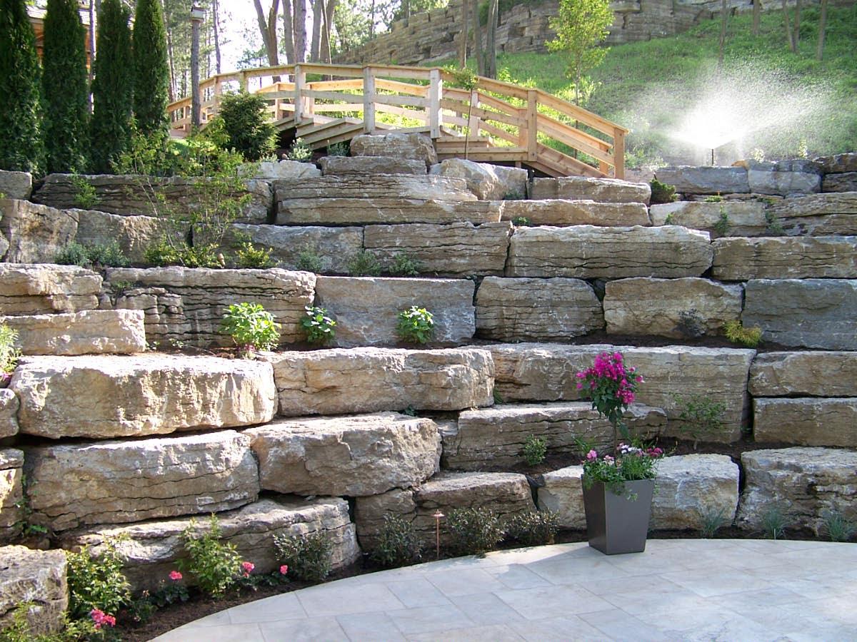 Natural stone retaining wall with tiered landscaping