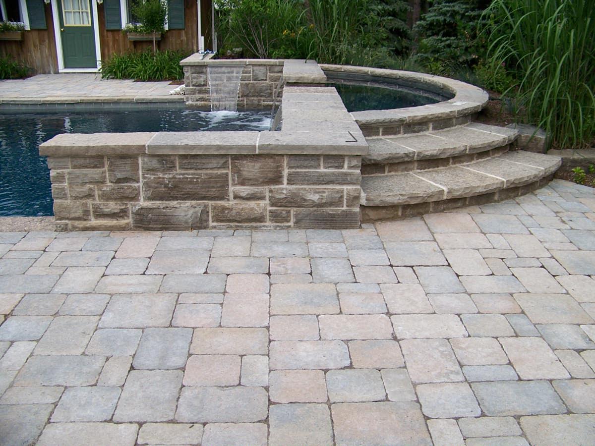 Stone pool steps with raised spa and patio pavers