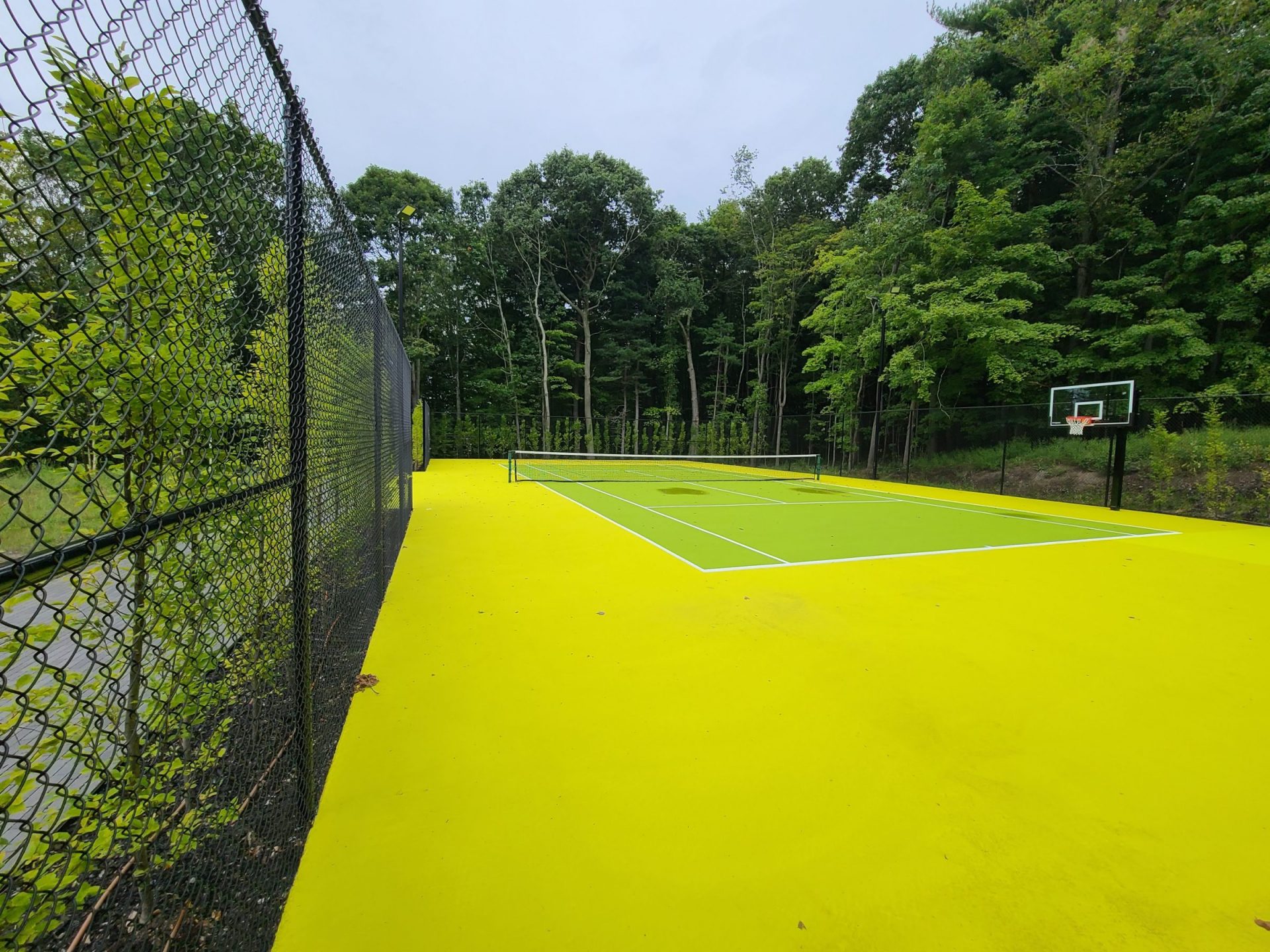 Vibrant yellow tennis and basketball court in forest.