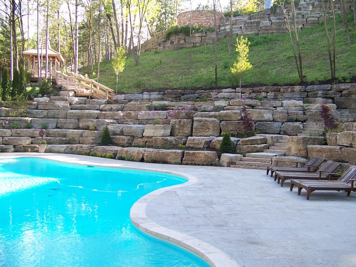 Outdoor pool with stone retaining wall and garden