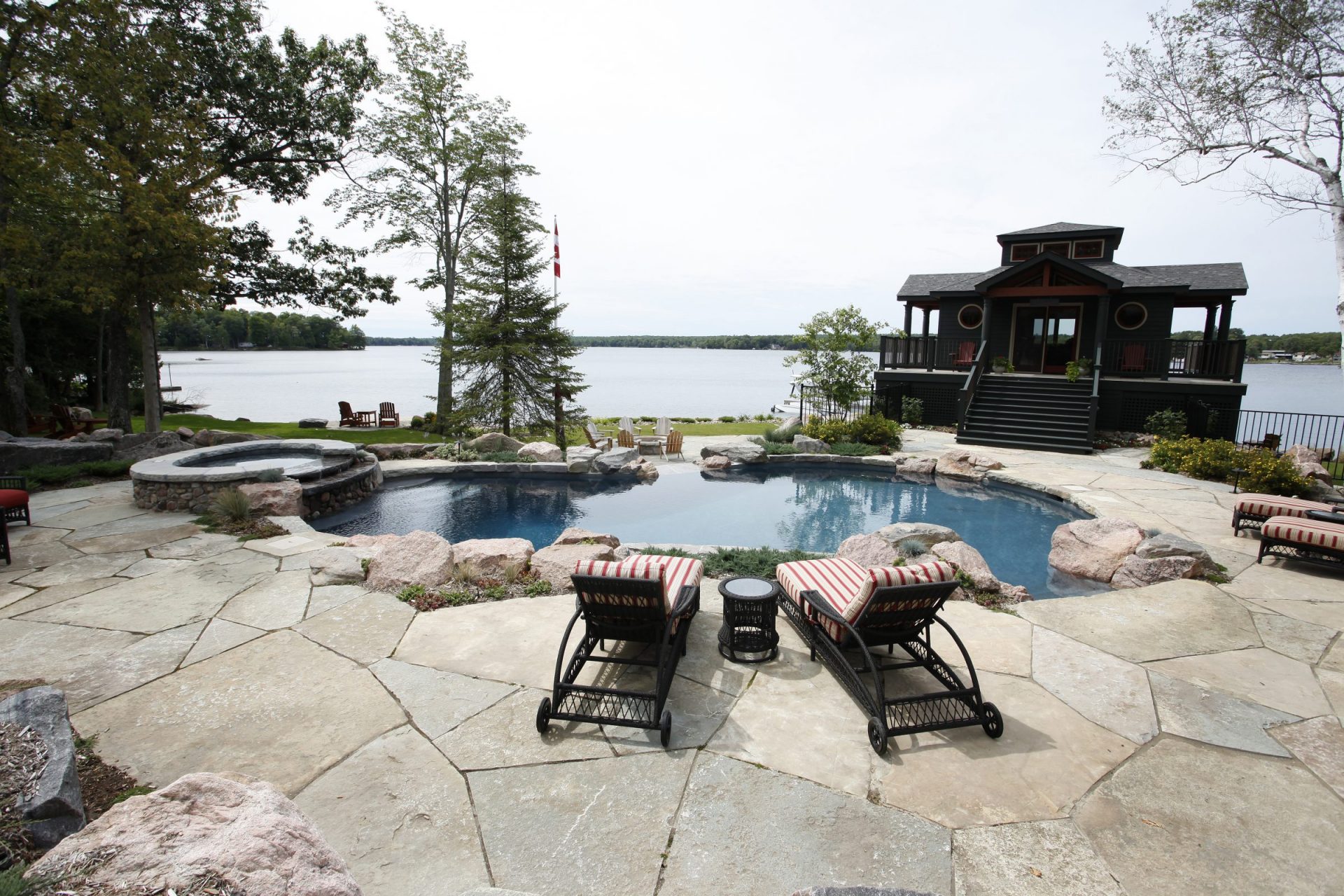 Lakefront patio with pool and Adirondack chairs.
